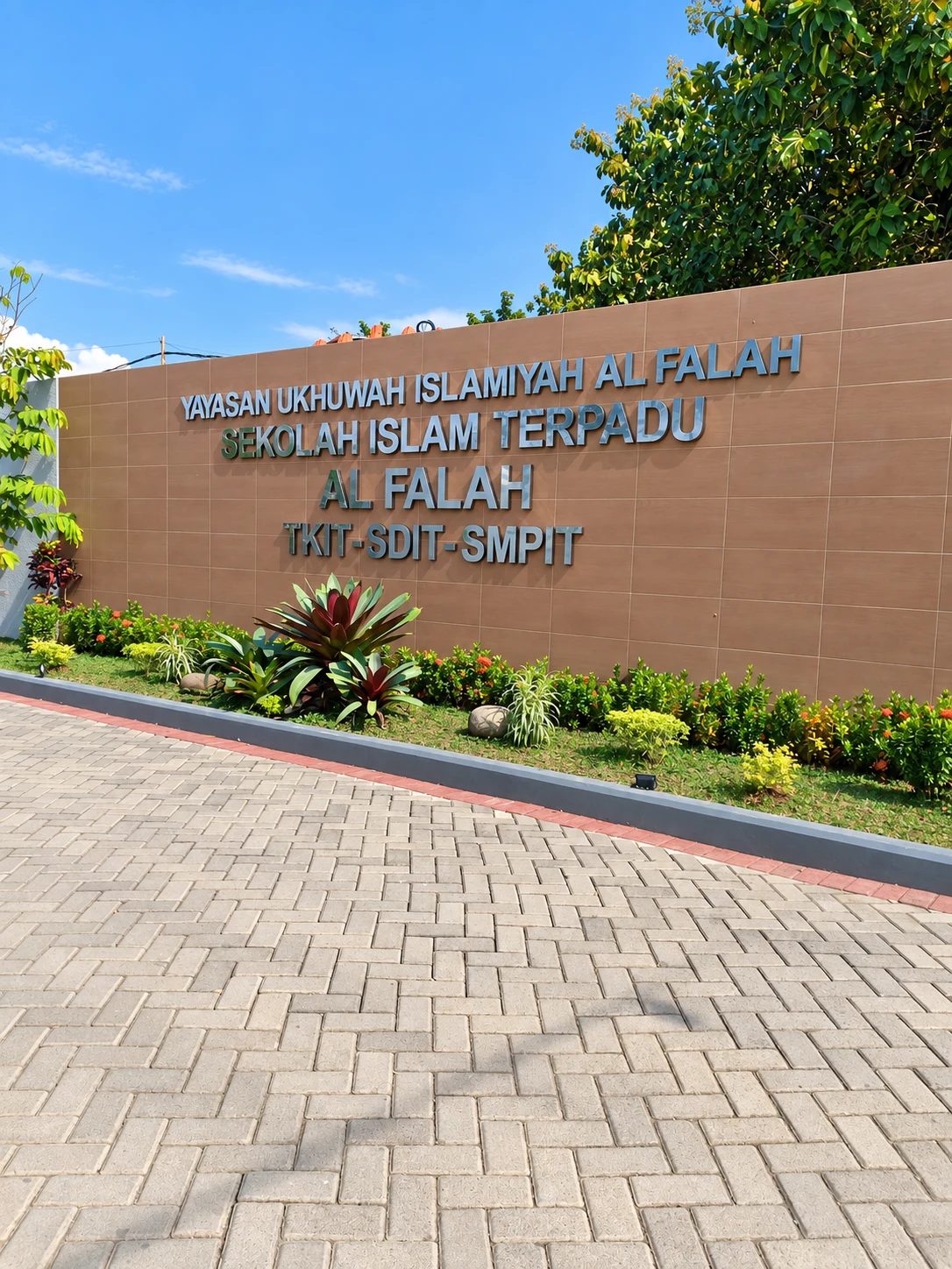 Papan nama Sekolah Islam Terpadu Al Falah dan taman di pintu masuk sekolah